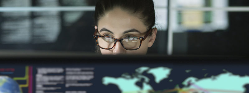 A woman working at a desk looking at data on world trade.